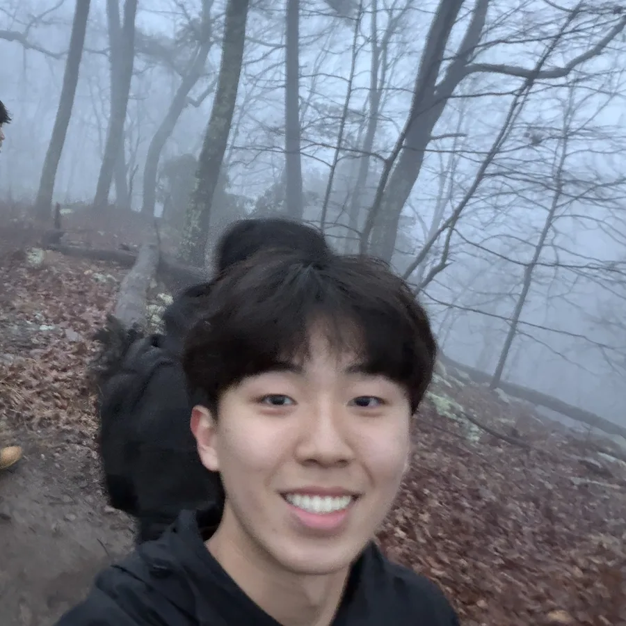 Justin Kong smiling on a foggy forest trail during a hike